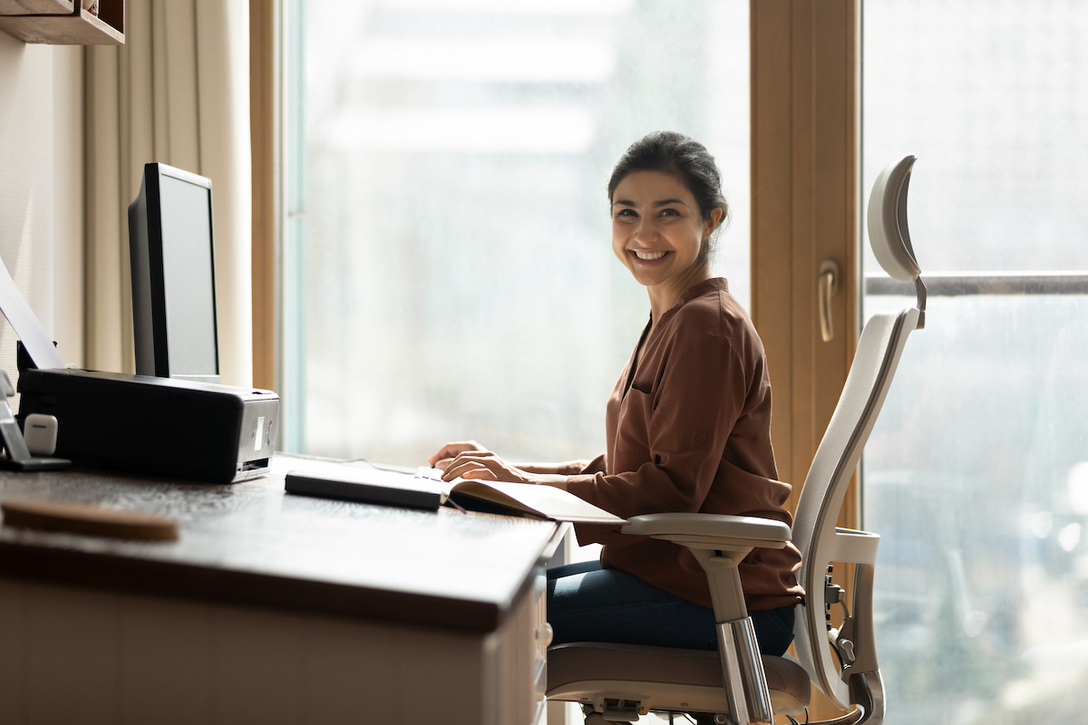 Office worker sitting upright at her desk.
